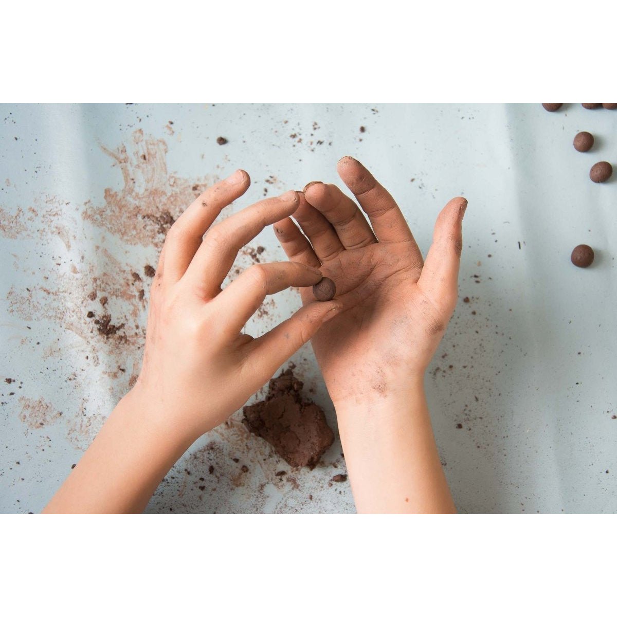 A child's hands making handmade seed balls.