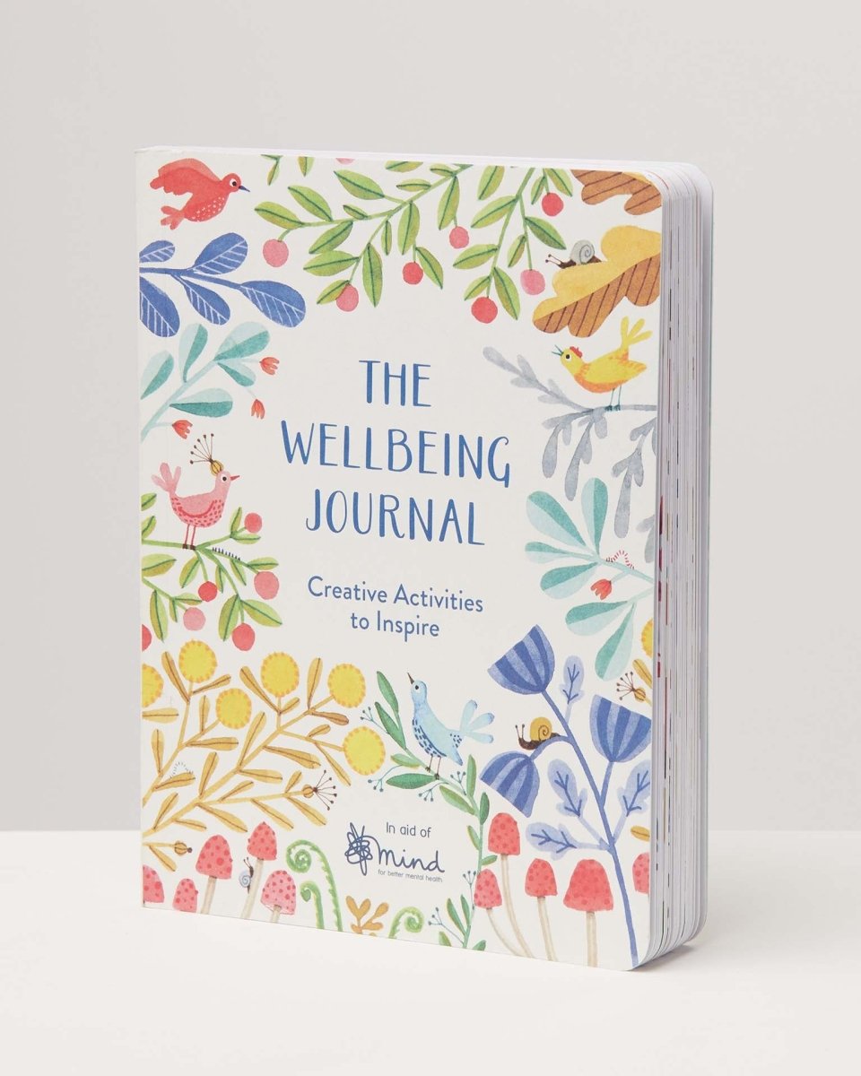 A colourful and illustrated wellbeing journal stood up against a white backdrop.