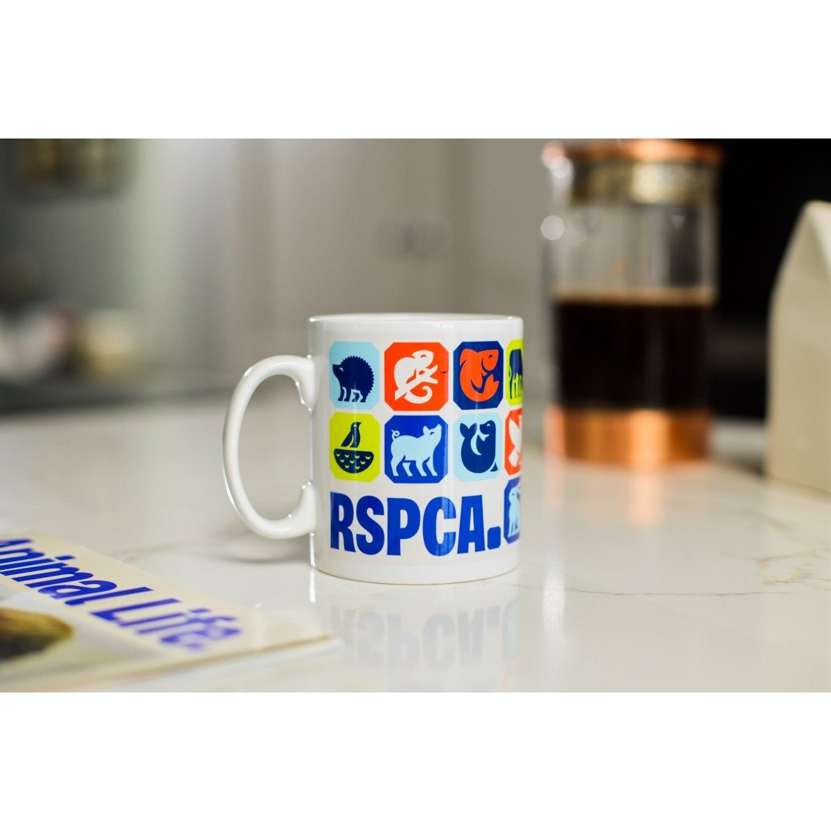 White mug with different animal graphics and the RSPCA logo printed on it. 