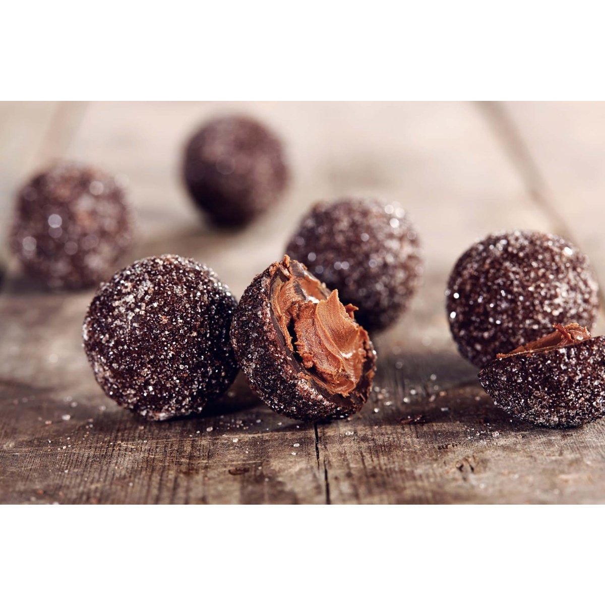 Six of the dark chocolate praline truffles, with one in half showing the praline filling.