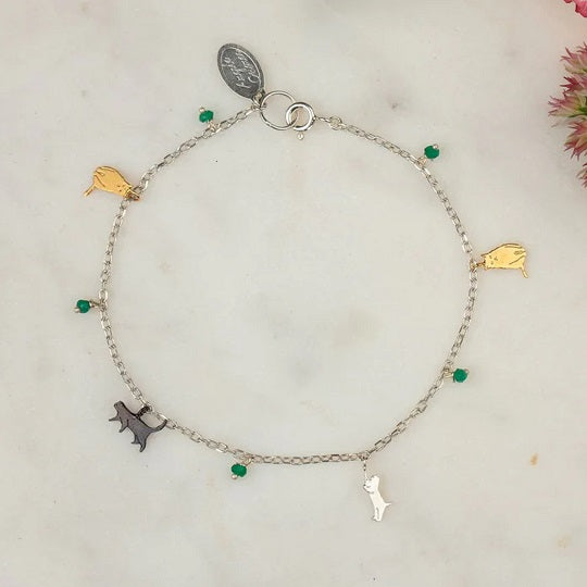 The Amanda Coleman Tiny Cats Charm Bracelet. A silver chain featuring little kittens and green stones.