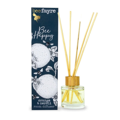 An orange and neroli scented glass diffuser next to a midnight blue gift box. 