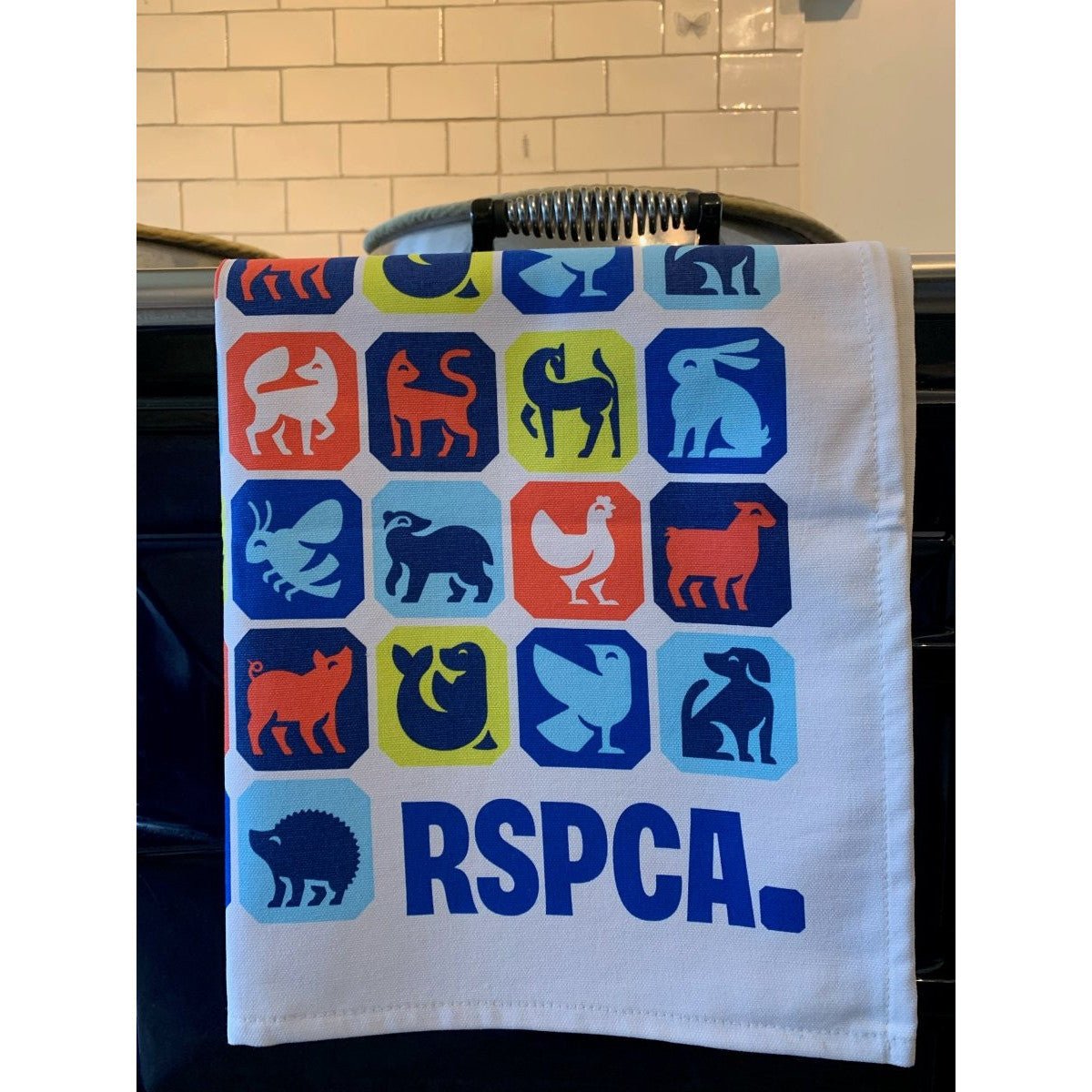 An RSPCA tea towel printed with different animal graphics and a blue RSPCA logo.